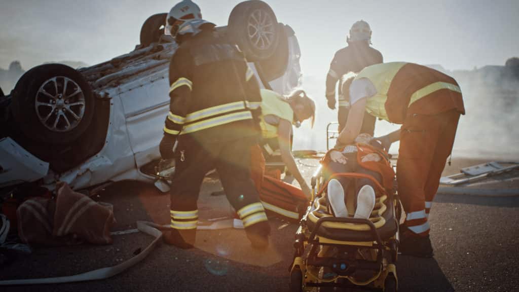 person receiving help from firemen after obtaining serious car accident injuries