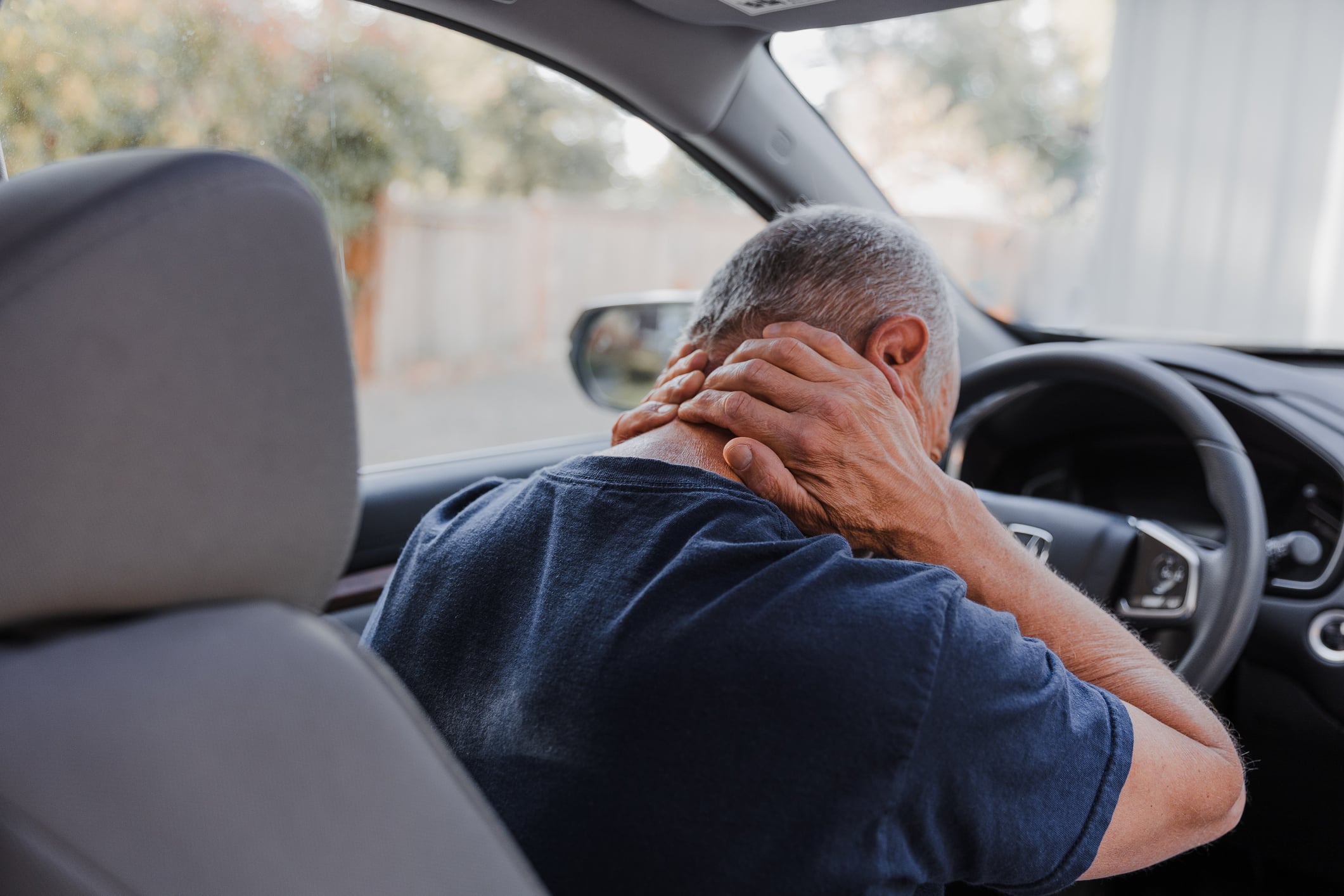 Man holding the back of his neck after an accident while needing to prove fault in a car accident